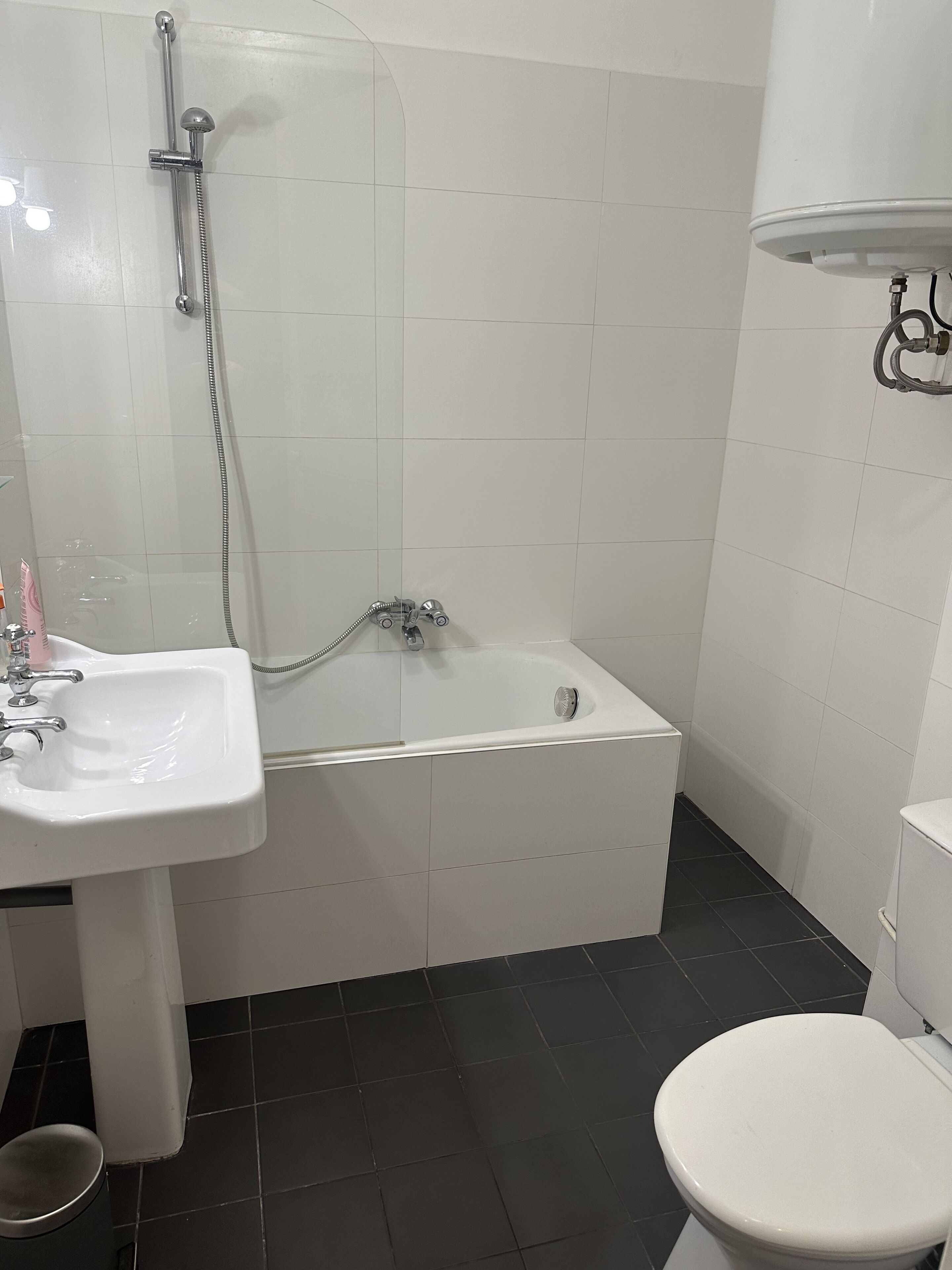 Une salle de bain avec un lavabo blanc, une baignoire et des toilettes.
