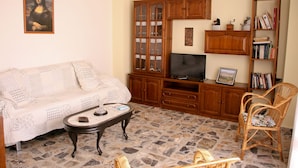 A living room with a sofa, coffee table, TV stand, wooden cabinets, wicker chairs, and a bookshelf. - Sol apartment ideal for large families and to visit the Monasterio de Piedra. (Munébrega)