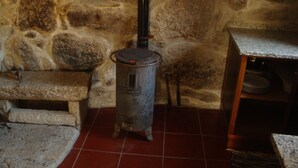 A stone wall, a small heater, a stone bench, and a tiled floor. - Quinta da Vinagra, sunny and modest space for up to 6 people (arcos de valdevez)