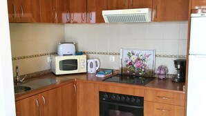 Une cuisine équipée d’armoires en bois, d’un four à micro-ondes, d’un grille-pain, d’une bouilloire, d’une machine à café et d’un réfrigérateur.