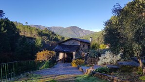 A stone building with a sloped roof, surrounded by a stone wall and a metal fence. - Mill rehabilitated with Natural Pool and Barbecue in natural environment  (Pinofranqueado)