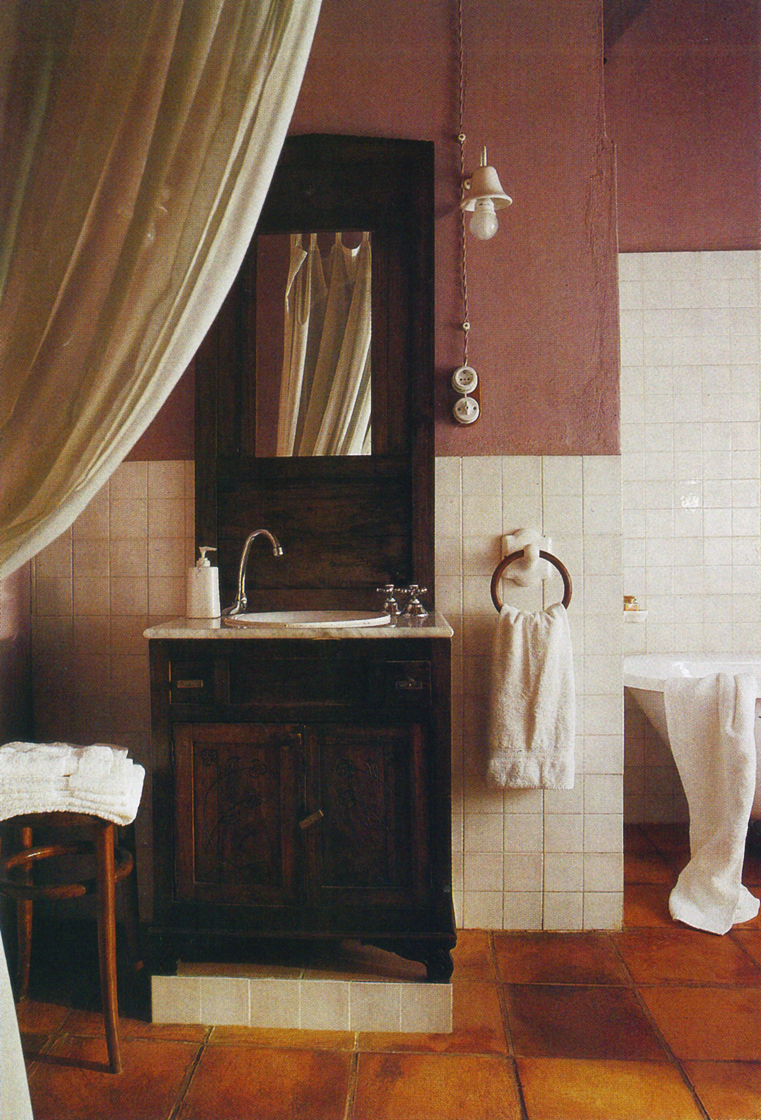 A bathroom with a wooden vanity, a mirror, a sink, a towel rack, and a hanging light fixture.