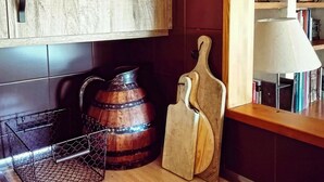 Une cuisine avec des meubles de rangement en bois, une étagère en métal, un tonneau en bois et une planche à découper.