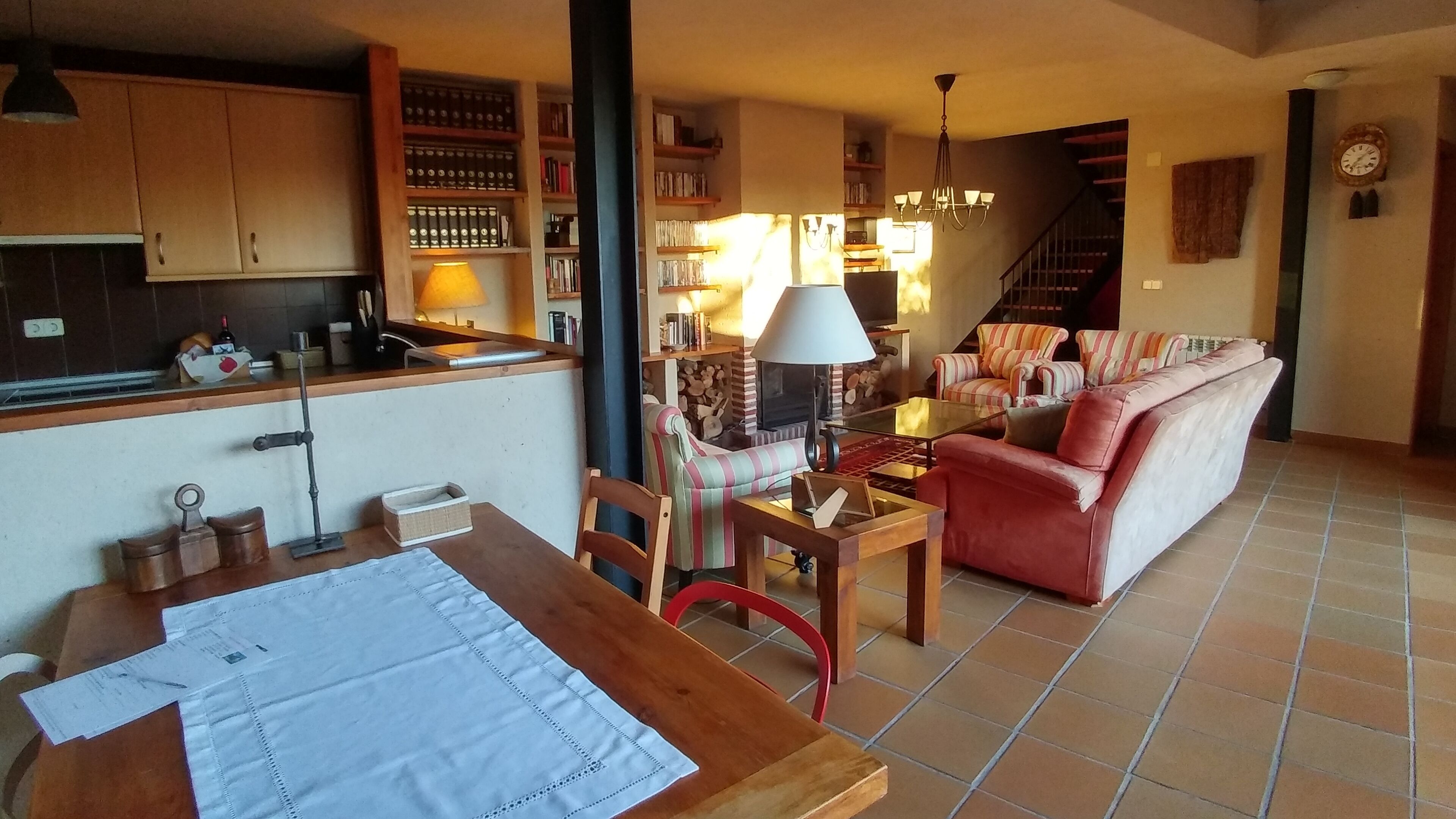 Una sala de estar acogedora con un sofá, una mesa de comedor con papeles, una lámpara y una chimenea.