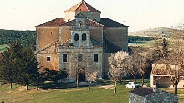 A large, historic building with a central tower and multiple windows, surrounded by a grassy area with trees and a stone structure. - The House of the Chickens for 4 people (Turrubuelo)