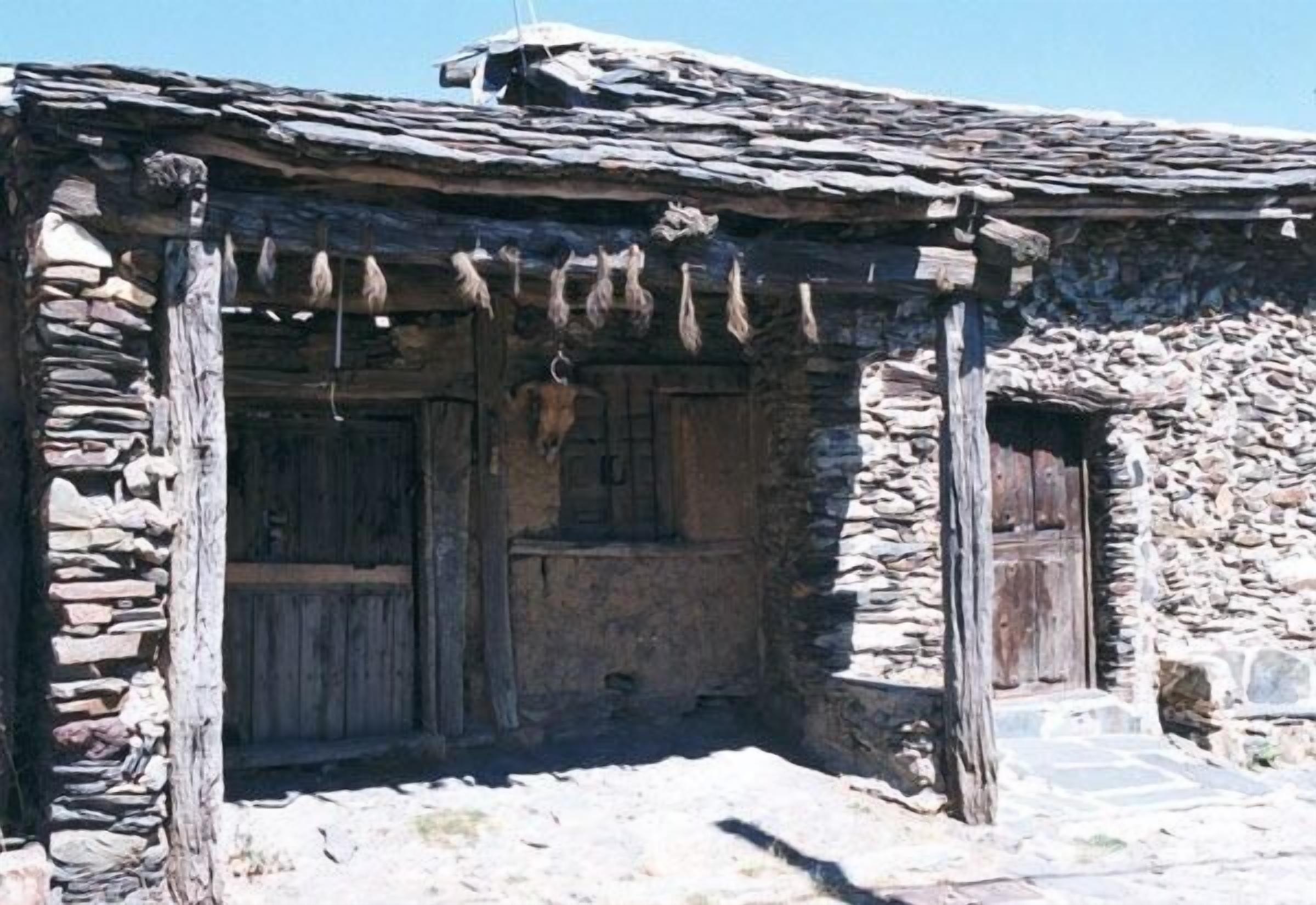 Un edificio rústico de piedra con puerta de madera y un pequeño porche.