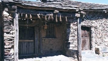 Un edificio rústico de piedra con puerta de madera y un pequeño porche.