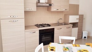Una cocina moderna con armarios de madera clara, una estufa a gas, horno empotrado y campana extractora de acero inoxidable.