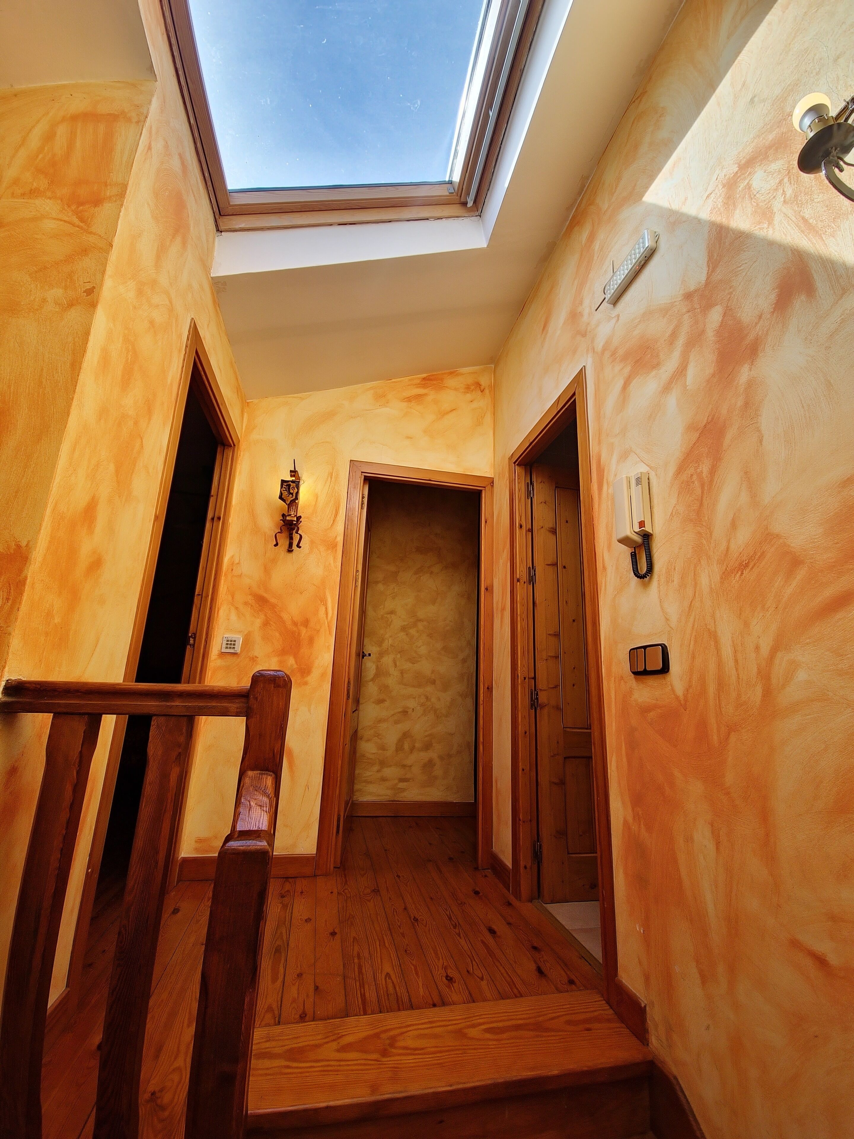 A wooden interior with a skylight, wooden flooring, and a staircase.