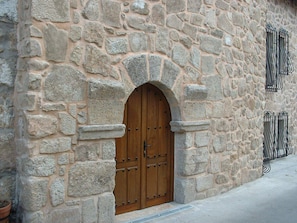 Un edificio de piedra con una puerta de madera grande y una ventana pequeña con barrotes.