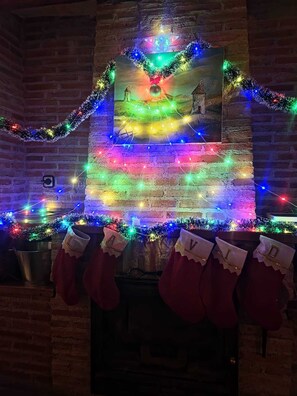 A fireplace with colorful Christmas lights and garlands, stockings with letters, and a framed picture above. - Casa Rural La Vid - Experiences, fireplace and group getaways (Cadalso de los Vidrios)