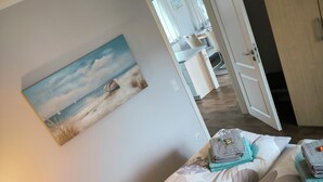 Ein Schlafzimmer mit Bett, Kissen, einem Gemälde und einem Nachttisch mit Lampe.