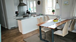Eine moderne Küche mit weißen Schränken, einer zentralen Kochinsel und einem Essbereich mit Holztisch und Stühlen.