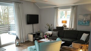 Ein modernes Wohnzimmer mit Sofa, Sessel und einem Flachbildfernseher.