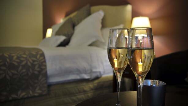Two glasses of white wine on a table with a bed in the background. - Black Spur Inn (Narbethong)
