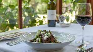 A table set with a plate of food, a wine bottle, and a wine glass. - Black Spur Inn (Narbethong)