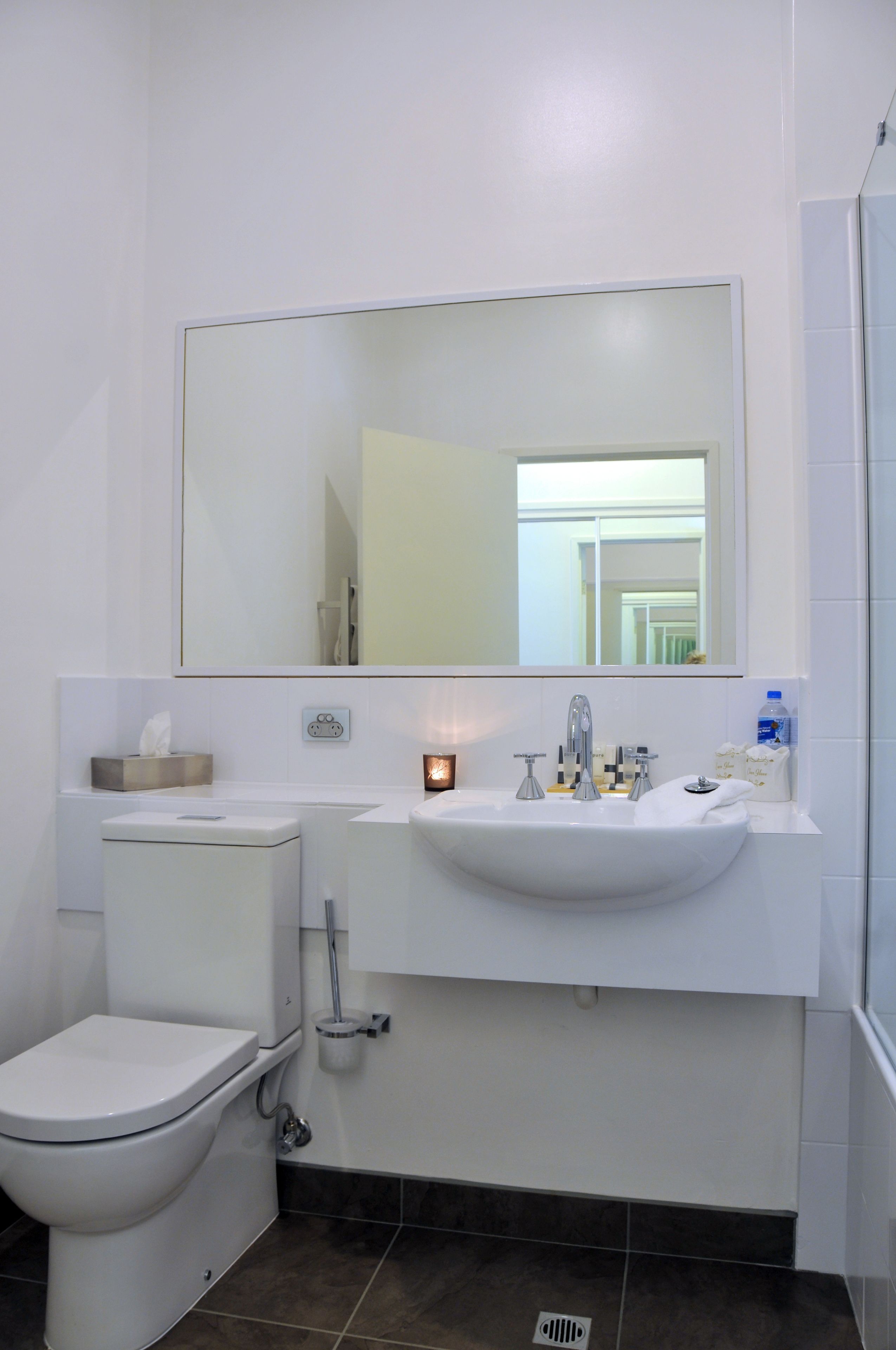 A bathroom with a toilet, sink, and mirror.