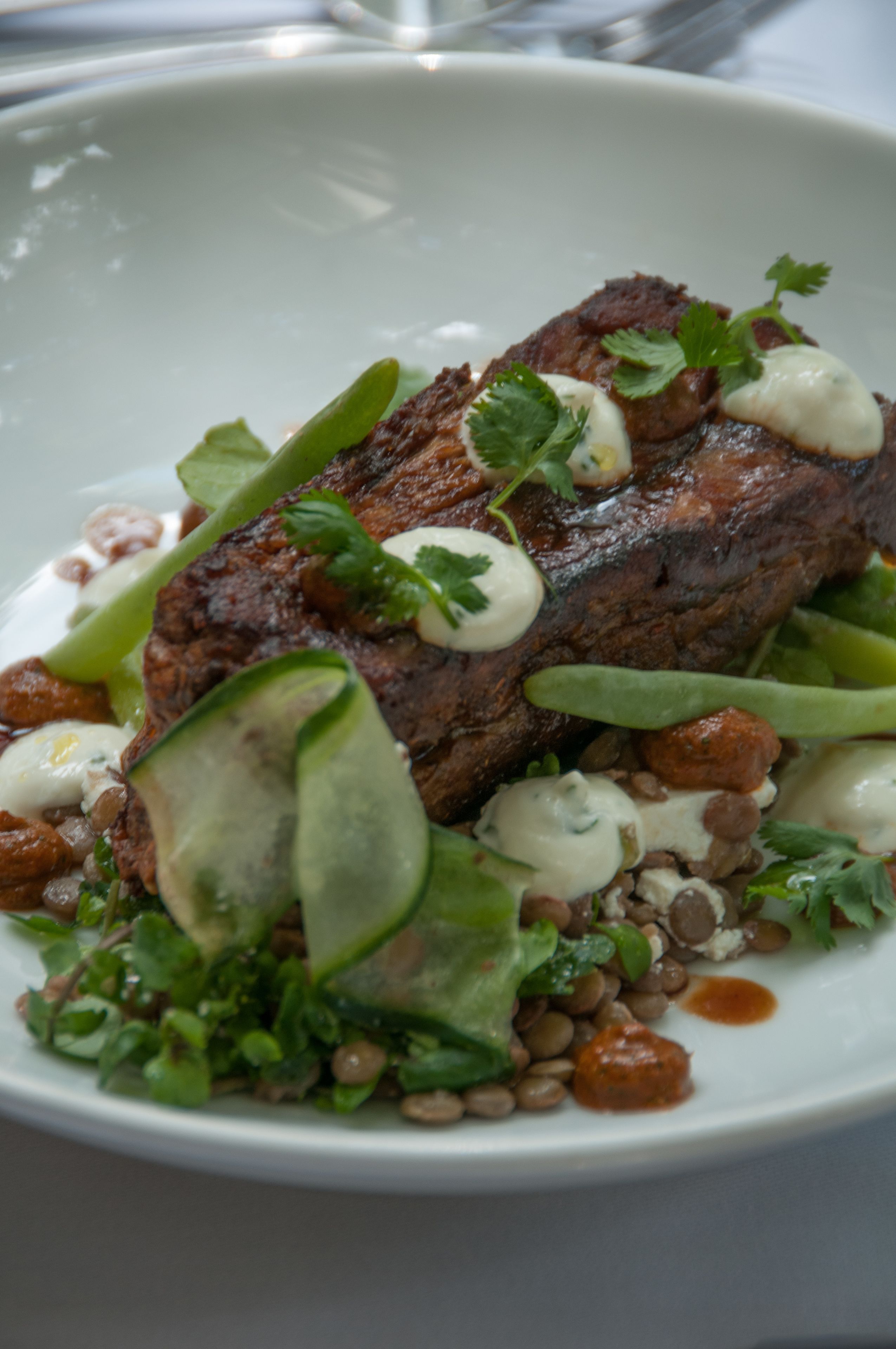 Un plato de comida con carne, verduras y salsa.