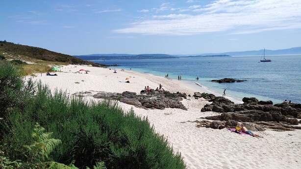 A beach with clear blue water, rocky areas, and people enjoying the sand. - Casa da Labaceira (for 7 people) (Cerdedo)