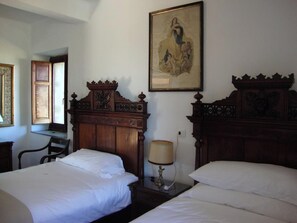 Une chambre d’hôtel avec deux lits, une tête de lit en bois, un bureau et une chaise.