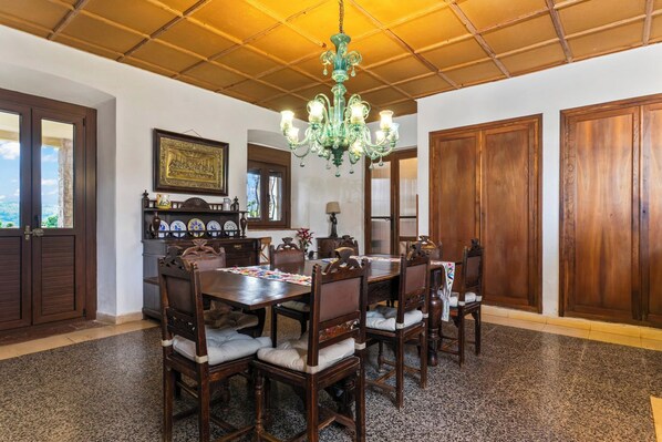 Un comedor con una mesa y sillas de madera, un candelabro y vistas a través de una ventana.