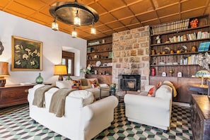 A cozy living room with a fireplace, a bookshelf, and a patterned floor.