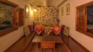 A cozy dining area with a stone wall, wooden furniture, and a table set for two. - Cottage Sunsets for 16 people (full rental) (Migueláñez)
