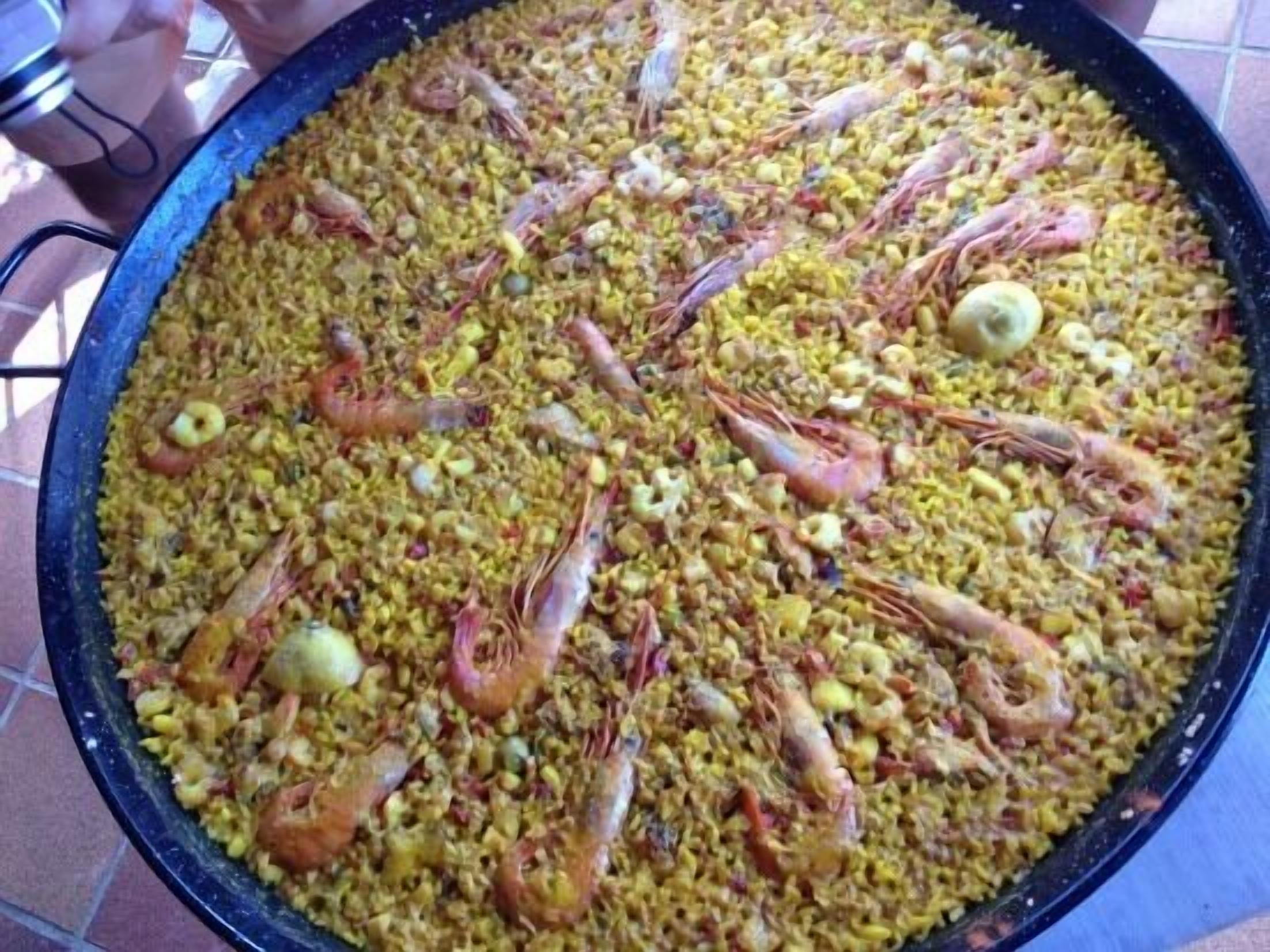 A large pan filled with paella, featuring shrimp and other ingredients.
