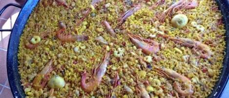 A large pan filled with paella, featuring shrimp and other ingredients.
