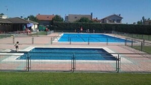 A rectangular swimming pool with a surrounding fence, a grassy area in the foreground, and buildings in the background. - Cottage Sunsets for 16 people (full rental) (Migueláñez)