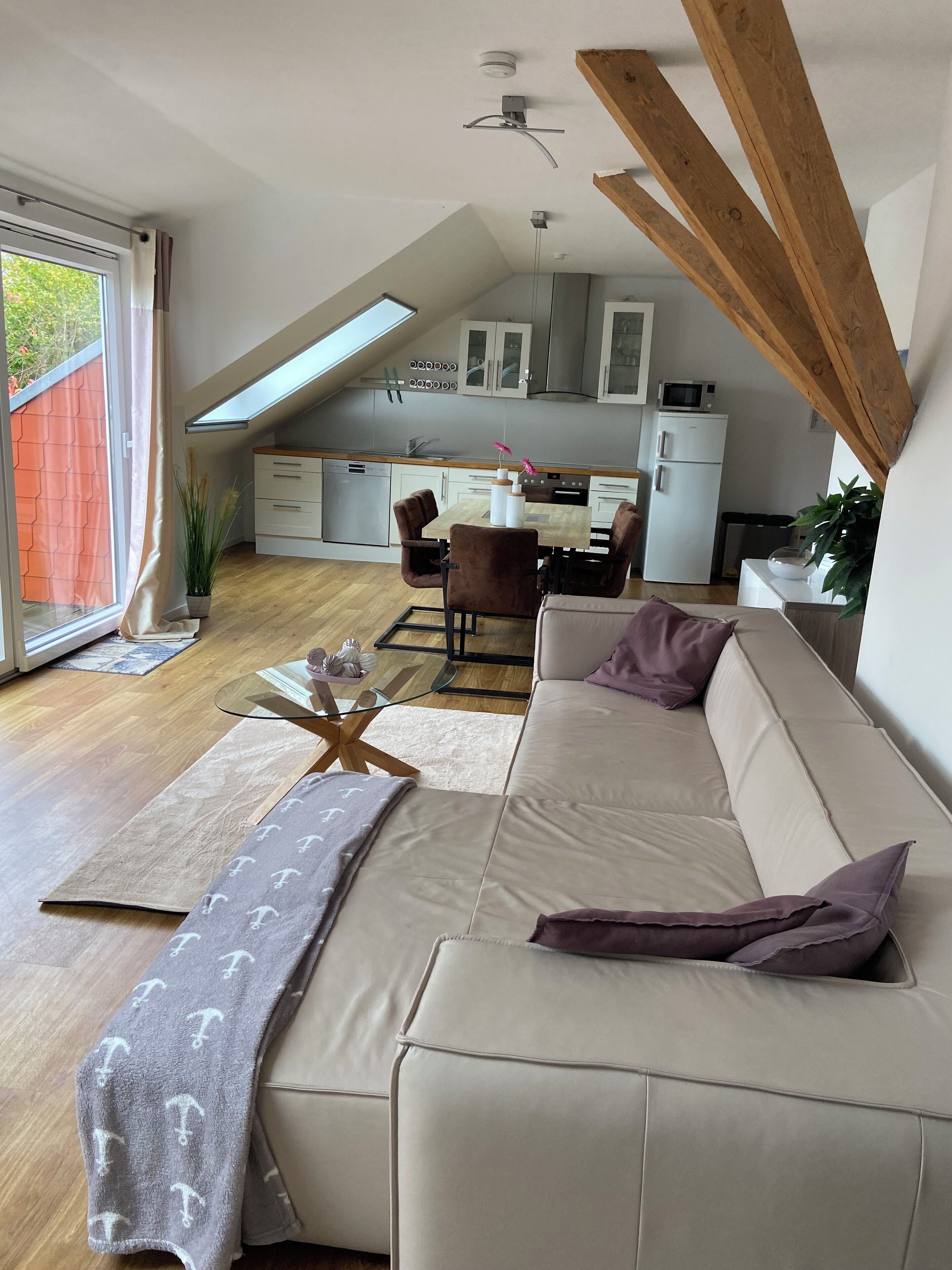 Ein modernes Wohnzimmer mit einer Couch, einem Glastisch und einem Essbereich mit Tisch und Stühlen.