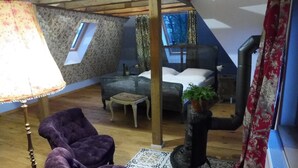 Een knus loft slaapkamer met een bed, een stoel, een klein tafeltje en een lamp.
