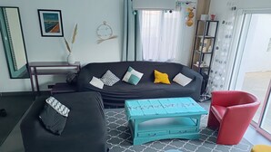 A modern living room with a black sofa, a teal coffee table, a red chair, and a black ottoman. - Family home 100m from the beach (Saint-Nazaire)