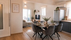 Una cocina moderna con comedor, un sofá y un televisor al fondo.