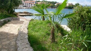 Un camino de piedra que conduce a la costa, con edificios al fondo.