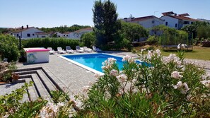Relax by the rectangular pool surrounded by a paved deck and lush greenery.
