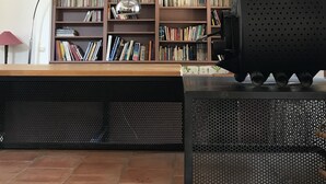 A room with a bookshelf, a black grill, and a tiled floor.