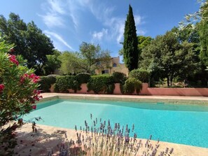 A swimming pool surrounded by lush greenery and a building in the background.