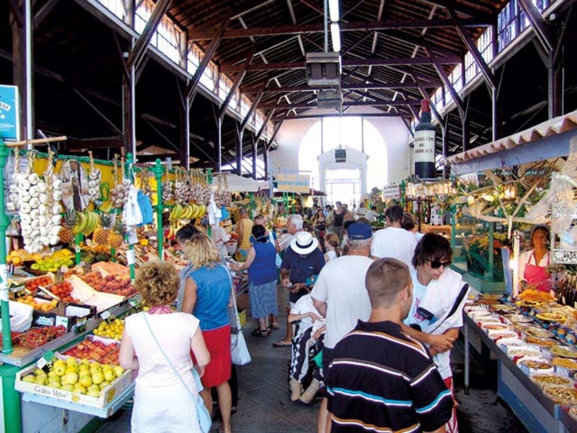 Ein lebhafter Innenmarkt mit verschiedenen Ständen, auf denen Obst, Gemüse und andere Waren angeboten werden.