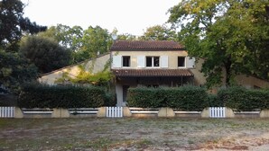 Ein zweistöckiges Haus mit Ziegeldach, weißen Fensterläden und einer überdachten Veranda.
