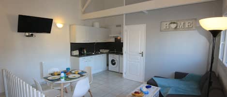 A compact living space with a dining area, kitchenette, and a sofa.