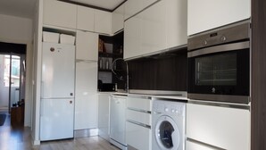 Eine moderne Küche mit weißen Schränken, einem eingebauten Geschirrspüler, einer Waschmaschine und einem Edelstahlbackofen.