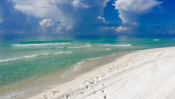 A beach with clear turquoise water, white sand, and a partly cloudy sky. - Bayfront Lodge-Beautiful & Unique East Bay Retreat (Gulf Breeze)