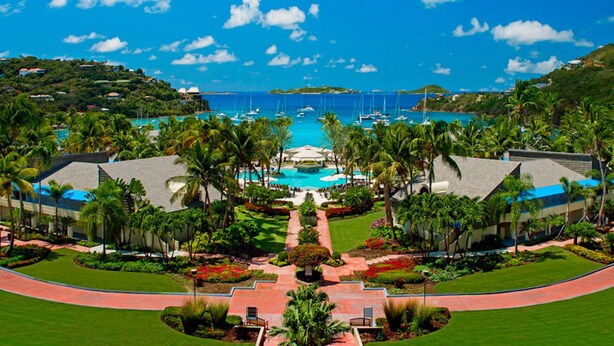 Ein Resort mit einem zentral gelegenen Pool, Palmen und Blick auf den Ozean.