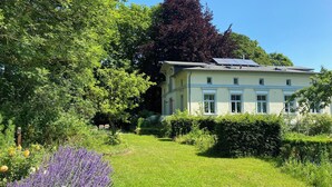 A two-story building with a garden in front, surrounded by trees and a variety of plants. - quiet holiday overlooking the pond, park and forest edge (Niederklütz)