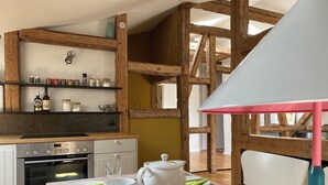 A kitchen with wooden beams, a stove, and a table set with a teapot, cups, and plates. - quiet holiday overlooking the pond, park and forest edge (Niederklütz)