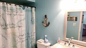 Een badkamer met toilet, wastafel en spiegel.