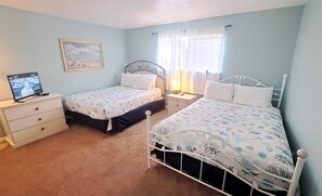 A bedroom with two single beds, a nightstand with a lamp, a dresser, and a framed picture on the wall. - Sunsets #1502 Chateau La Mer II 2Bd-2Bath Ground Floor (Destin)
