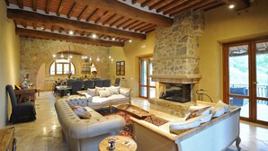 Amplia sala de estar con chimenea de piedra, asientos cómodos y vistas al exterior.