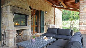 Una chimenea de piedra con fuego, un sofá y una mesa con tazas y una cesta.